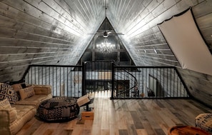 An attic bedroom with a sloped ceiling, a chandelier, a staircase, and a view of the sky.