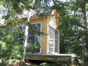 Una cabaña de madera con ventanas grandes, rodeada de árboles.