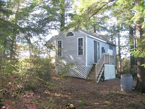 A small cabin with a wooden deck and a staircase leading to the entrance.