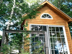 A wooden cabin with a large window and a small dormer window.