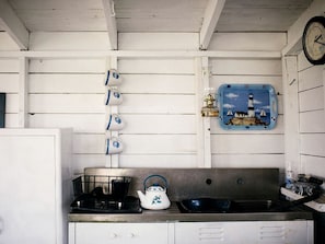 A kitchen with a stove, kettle, sink, and wall-mounted kettle.