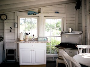 A kitchen with white cabinets, a stove, a window, and a clock on the wall.