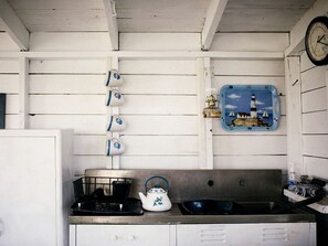 A kitchen with a stove, kettle, sink, and wall-mounted kettle.