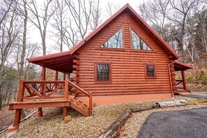 A log cabin with a porch, a staircase, and a window.