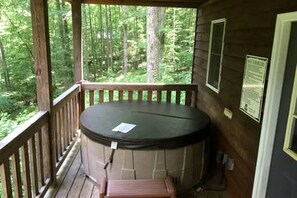 Ein Whirlpool auf einer Holzterrasse mit Blick auf einen Wald.