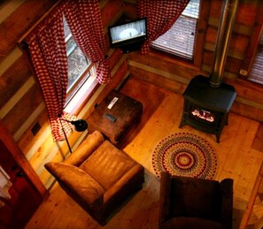 L’intérieur d’un chalet accueillant, avec un canapé, une petite table, un téléviseur, une cheminée et un tapis à motifs.