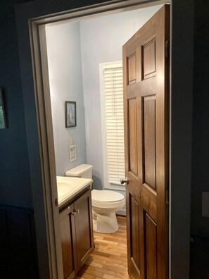 A bathroom with a toilet, a sink, and a window with blinds.