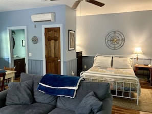 Une chambre à coucher avec un lit, une table de chevet, une lampe, une horloge murale et un ventilateur de plafond.