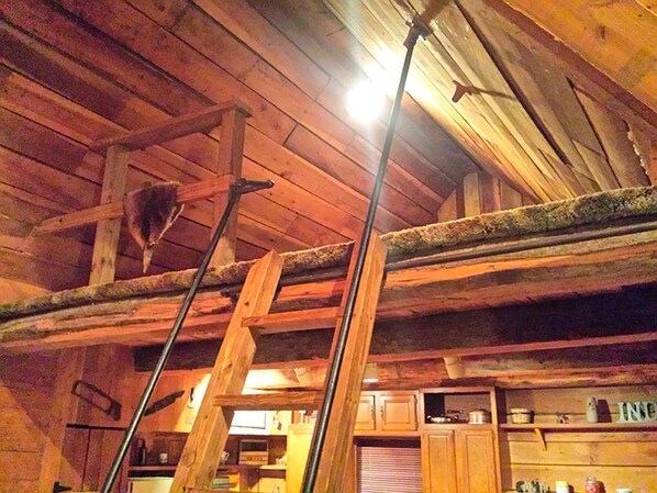 A rustic wooden interior with a ladder, wooden beams, and a kitchen area. - Charmingly Rustic Weekend Getaway in the Mountains near Pittsburgh, Pennsylvania (Champion)