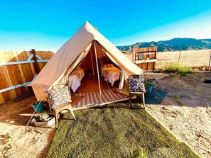 Una carpa con vista a las montañas, una cerca de madera y una silla con cojín.