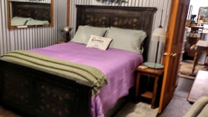 A bedroom with a bed, a nightstand, a lamp, a mirror, and a door. - Charming Farmhouse Glamping Cabin in Sparta, Tennessee (Sparta)