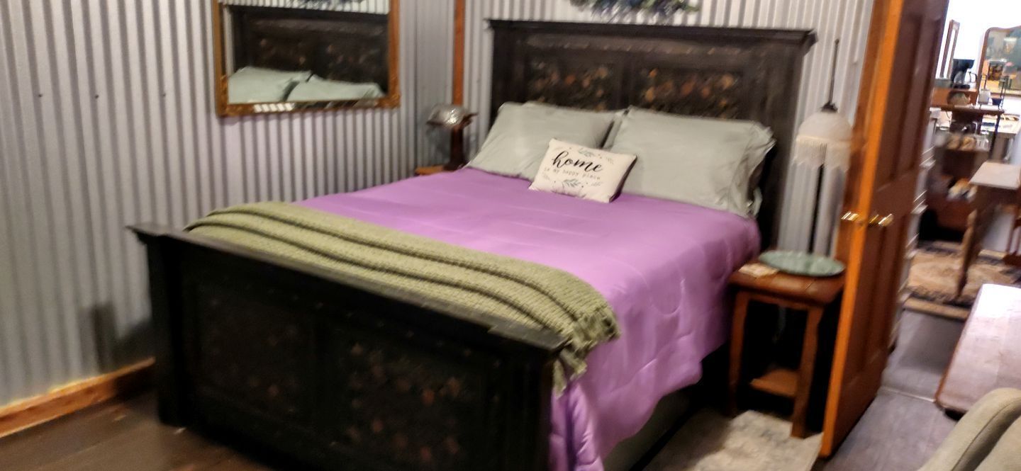 Ein Schlafzimmer mit Bett, Nachttisch, Lampe, Spiegel und Tür.
