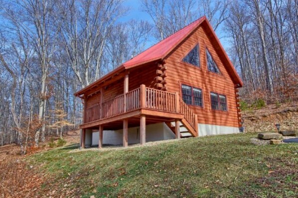 A log cabin with a balcony, a large window, and a porch.
