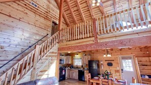 L’intérieur d’un chalet en bois comprend une cuisine, un coin repas et un escalier menant à un étage supérieur.