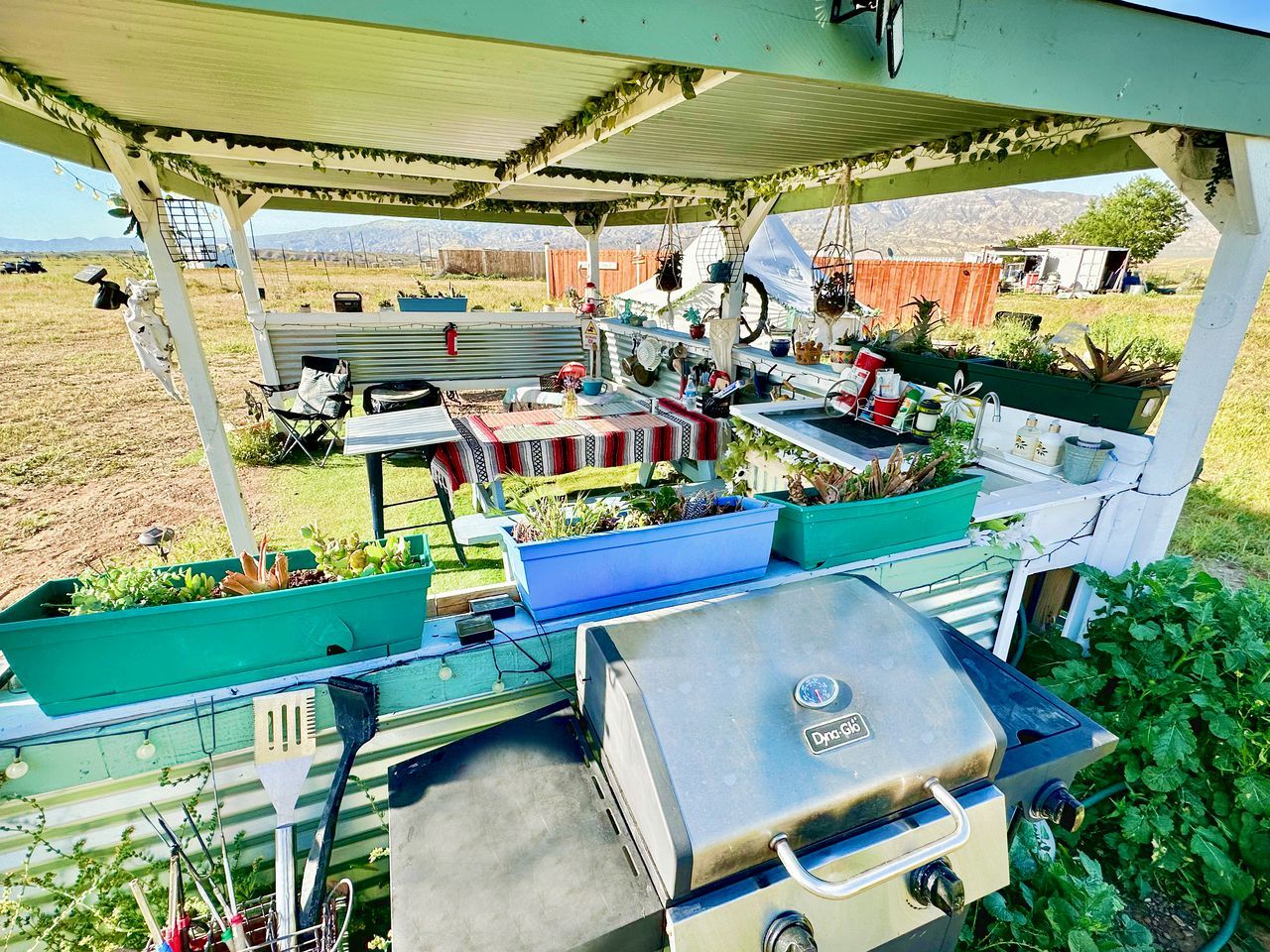 An outdoor patio with a grill, seating, and planters.