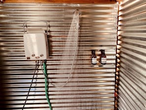 A shower with a control box and two bottles of shampoo.