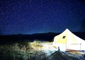 A tent in a natural setting with a starry night sky.