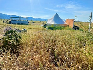 Una carpa en un campo con montañas al fondo.