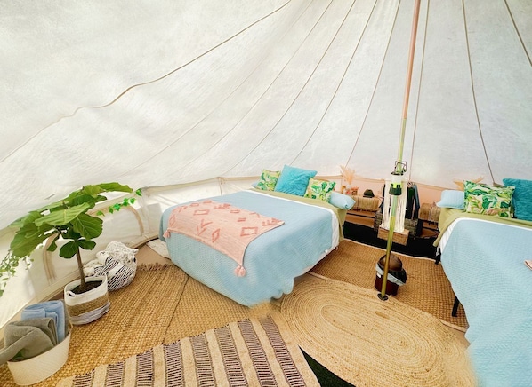 A tent with two beds, a hanging chair, and a small table.