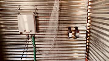 A shower with a control box and two bottles of shampoo.