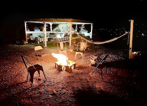 A covered outdoor seating area with chairs and a fire pit.