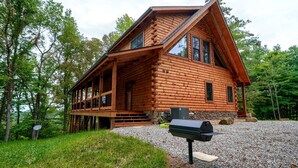 A log cabin with a porch, a grill, and a gravel driveway. - Lovely Logan Log Cabin Retreat for Family and Group Glamping in Ohio (Logan)