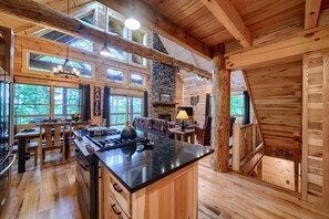 Una cocina amplia con una isla central, paredes de madera y ventanas grandes.