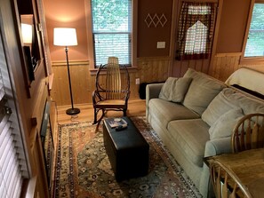 A cozy living room with a sofa, a wooden rocking chair, a floor lamp, and a patterned rug. - Luxury Cabin Rental with Beautiful Water Views near Charlotte, North Carolina (Elkin)