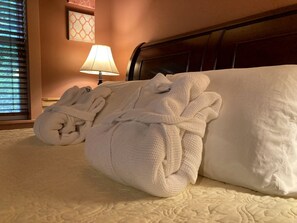 A neatly made bed with white linens and a pillow, a bedside lamp, and a wall art piece. - Luxury Cabin Rental with Beautiful Water Views near Charlotte, North Carolina (Elkin)