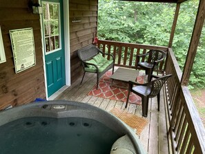 Terraza de madera con un jacuzzi, una puerta verde y un letrero.