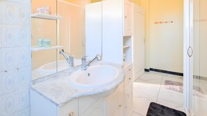 Un baño con dos lavamanos, un espejo y una zona de ducha.