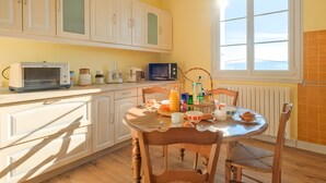 Una cocina con armarios blancos, un microondas y una mesa de comedor con sillas.