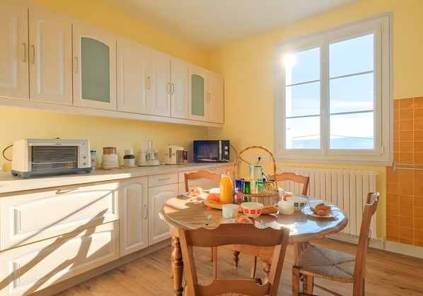 Une cuisine avec des meubles blancs, un four à micro-ondes et une table à manger avec des chaises.