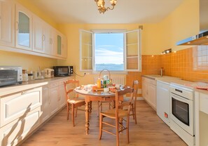 Une cuisine équipée d’une table à manger, de chaises, de placards, d’un four à micro-ondes et d’une fenêtre donnant sur un paysage dégagé.