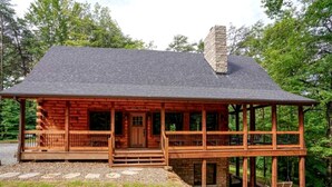 A log cabin with a porch, a chimney, and a stone foundation. - Hocking Hills Park Getaway for Family Adventures in Logan, Ohio (Logan)
