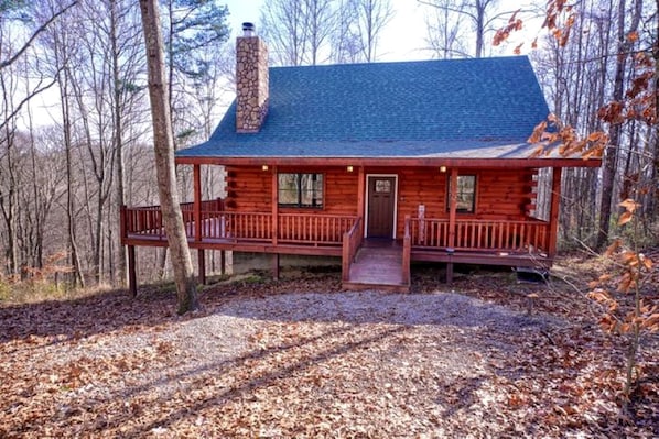A log cabin with a porch, a chimney, and a door.
