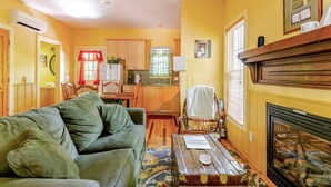 A cozy living room with a green sofa, a wooden coffee table, and a fireplace. - Rustic Cabin on 28-Acre Property in the Foothills of the Blue Ridge Mountains (Elkin)