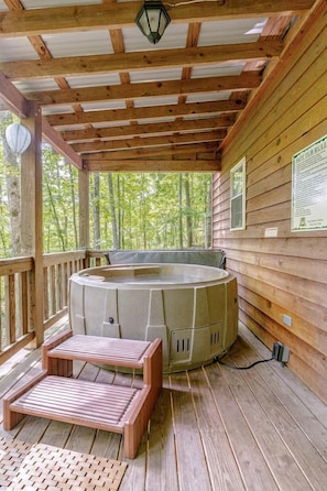 En træterrasse med jacuzzi, trætrapper og gelænder i træ.