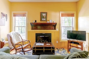 A living room with a fireplace, a television, and a cozy seating area. - Rustic Cabin on 28-Acre Property in the Foothills of the Blue Ridge Mountains (Elkin)