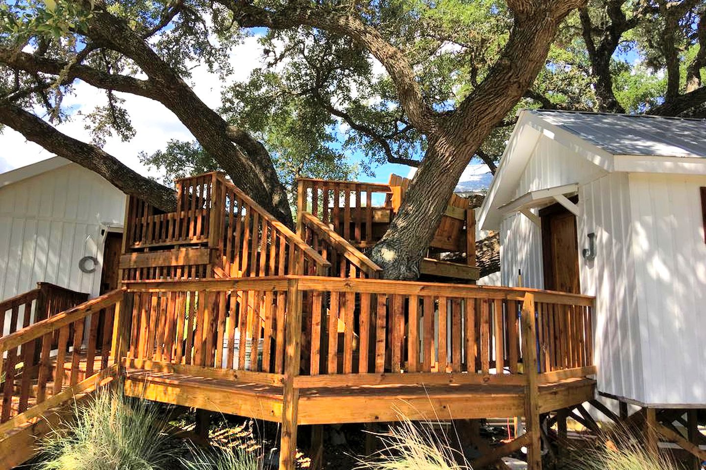 Une terrasse en bois avec un escalier menant à un bâtiment blanc doté d’une porte.