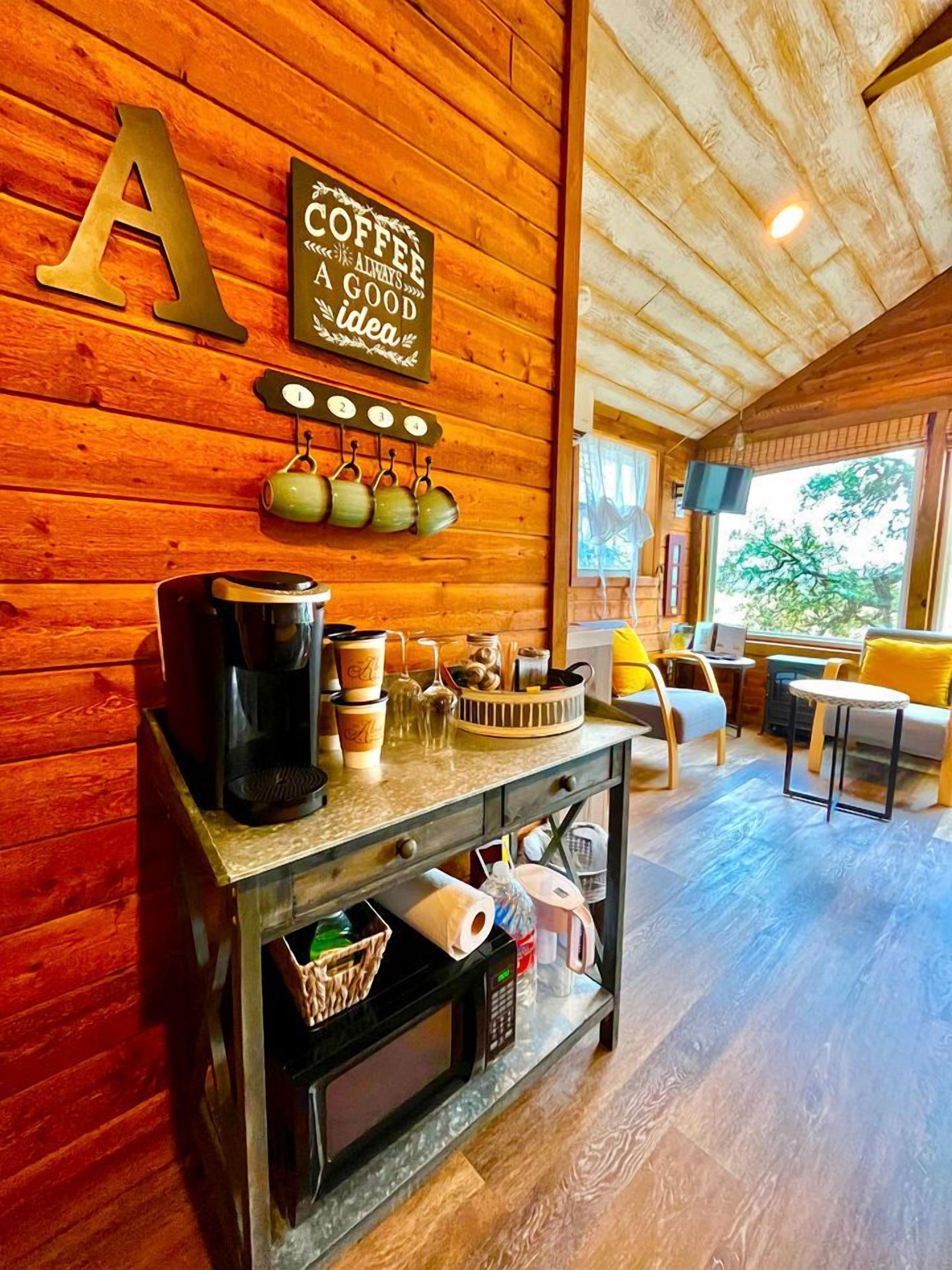 Un intérieur en bois avec un coin café, une grande décoration en forme de « A » et une vue sur l’extérieur.