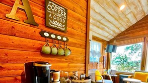 Ein Holzinterieur mit einer Kaffeestation, einer großen 'A'-Dekoration und Blick ins Freie.