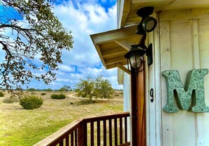 A wooden porch with a railing, a lamp, and a large 'M' sign on the wall.