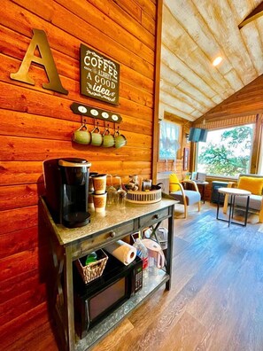 A wooden interior with a coffee station, a large 'A' decoration, and a view of the outdoors.