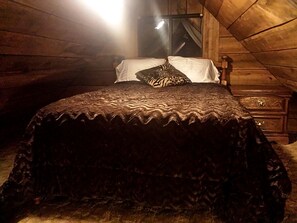A bed with a patterned bedspread in a room with wooden walls and a window. - Cozy Vacation Rental with High-Speed Wi-Fi near Seven Springs, Pennsylvania (Champion)