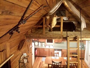 A rustic cabin interior with a dining area, kitchen, and a sleeping loft. - Cozy Vacation Rental with High-Speed Wi-Fi near Seven Springs, Pennsylvania (Champion)