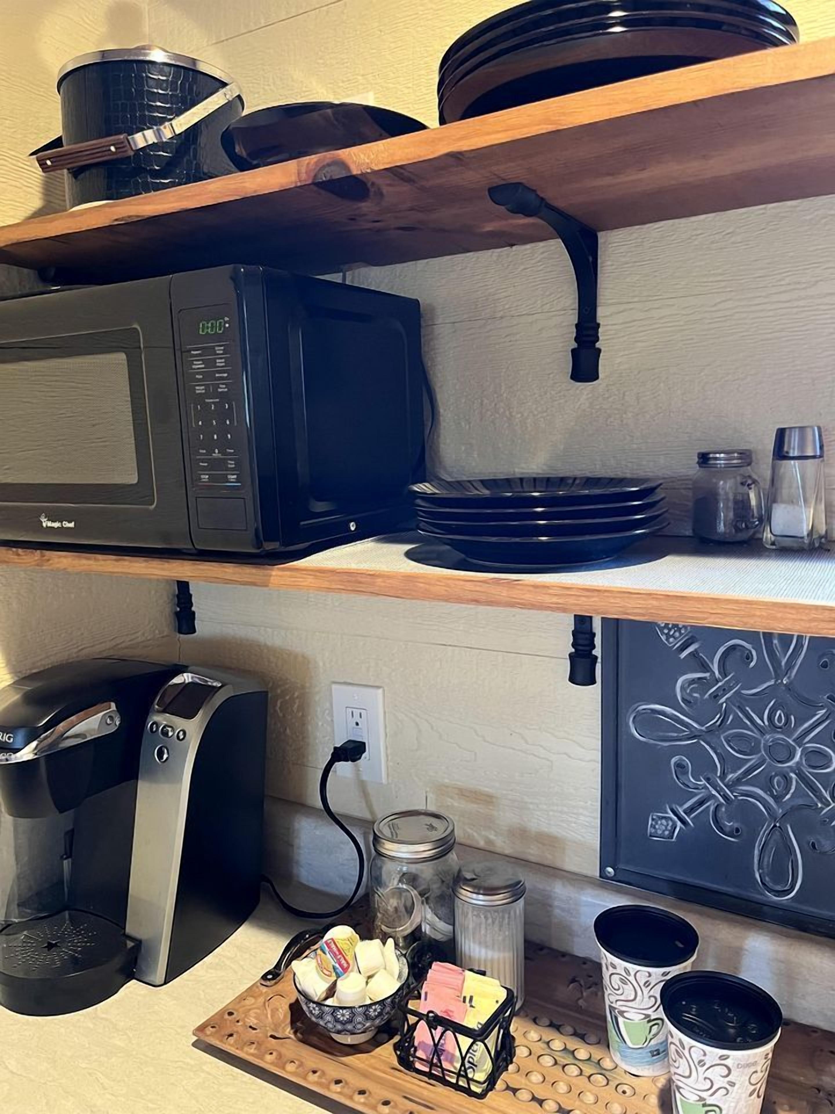 A kitchen with a microwave, toaster, and various kitchen items on shelves.