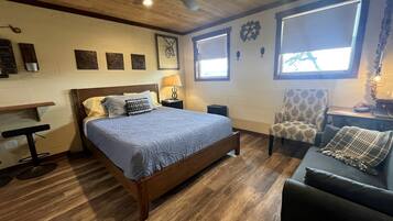 A bedroom with a bed, a chair, a desk, and a ceiling fan.