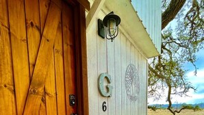 A wooden door with a number '6' and a letter 'G' on the wall, a mailbox, and a tree in the background. - Peaceful Texas Hill Country Rental Perfect for Glamping Around Austin (Dripping Springs)