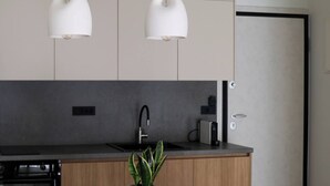 Eine moderne Küche mit einem Holztisch, zwei Stühlen, einer Topfpflanze und Pendelleuchten.
